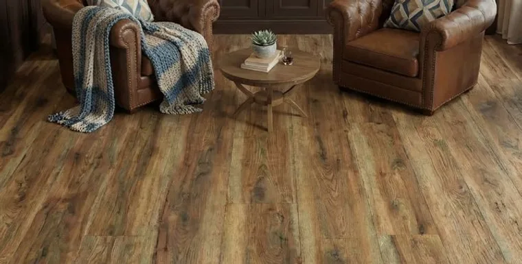 Wood flooring in a living room with leather armchairs and a round table