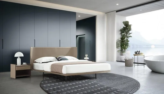 Bedroom with a beige platform bed, a floor-to-ceiling wardrobe and a freestanding bathtub