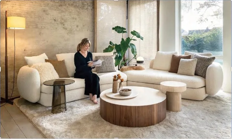 Living room with a white boucle sofa, a round coffee table and a tall floor lamp