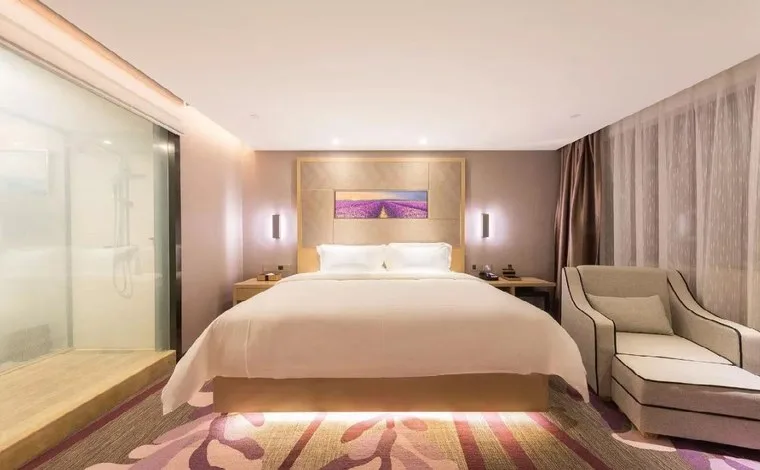 Hotel guest room with a king bed and a glass shower